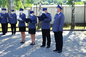 policjant czyta rozkaz. Obok niego stoją policjanci