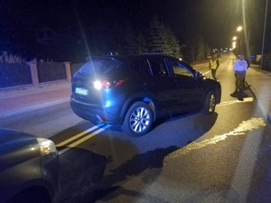 skradziona mazda stoi na ulicy, a obok stoi oznakowany radiowóz na sygnałach świetlnych