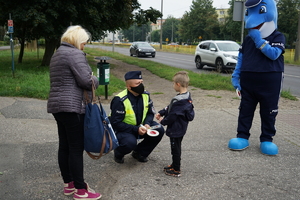 Policjant wręcza dziecku opaskę odblaskową.