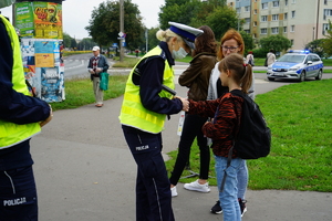 Policjantka wręcza dziecku opaskę odblaskową.