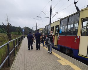 Policjanci na przystanku tramwajowym. Pasażerowie wysiadają z tramwaju.