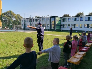 Policjantka rozmawia z uczniami na terenie przyszkolnym.