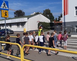 Policjantka przechodzi z dziećmi przez przejście dla pieszych.