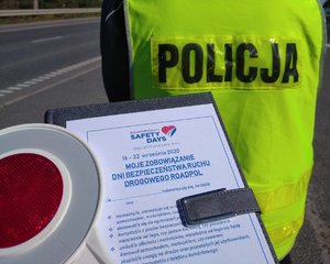 Deklaracja, tarcza do zatrzymywania pojazdów na tle kamizelki odblaskowe z napisem policja