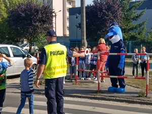 Uczniowie pod okiem policjantów i polfinka przechodzą przez przejście dla pieszych.