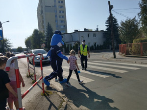 Dzieci ćwiczą właściwe przechodzenie przez jednię w towarzystwie policjantów.