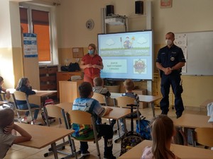 Uczniowie i policjanci podczas zajęć w klasie szkolnej.