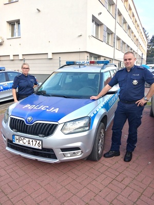 dzielnicowa mł. asp. Joanna Wesołowska i dzielnicowy asp. Michał Kaczorowski stoją obok radiowozu na parkingu