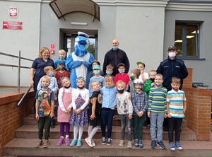 Zdjęcie grupowe uczestników spotkania na schodach wejściowych do budynku placówki.