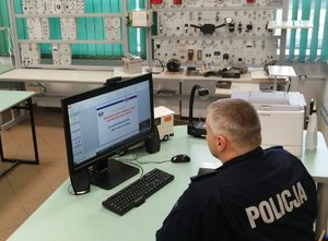 Policjant w sali lekcyjnej podczas zajęć on-line z uczniami.