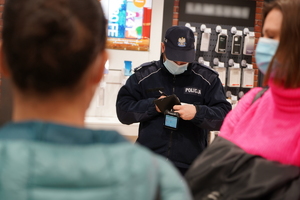 policjant i dwie pracownice sanpeidu kontrolują jeden z sklepów w galerii handlowej. Policjant sprawdza dane