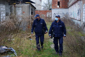 Policjanci idą pomiędzy pustostanami.