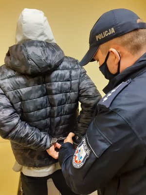 Policjant zakłada kajdanki zatrzymanemu. Ujęcie z bliska.