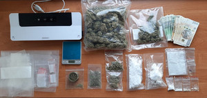 zabezpieczone narkotyki, pieniądze i sprzęt do pakowania narkotyków leżą na stole