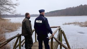 Policjant i leśnik podczas patrolu obserwują (stojąc na pomoście) tereny przywodne i leśne.