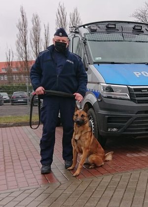 Krzysztof Dąbrowski ze swoim psem stoją przy radiowozie.
