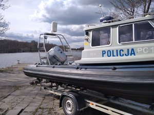 Policyjna łódź motorowa na wózku stoi na brzegiem rzeki.