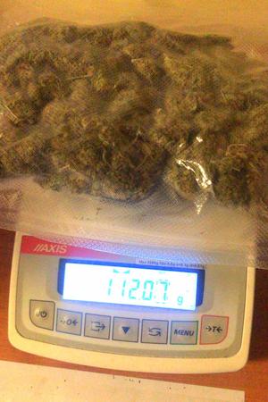 zapakowana hermetycznie marihuana leży na wadze. Waga wskazuje 112,07 g