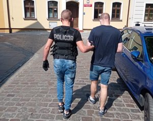 Policjant prowadzi zatrzymanego.