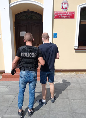 Policjant wprowadza zatrzymanego do prokuratury.