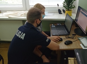 Policjanci podczas spotkania on-line z uczniami siedzą przed komputerem.