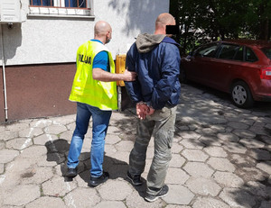 Policjant prowadzi zatrzymanego do komisariatu.