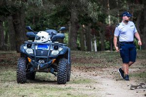 Policyjny quad. Obok idący policjant.