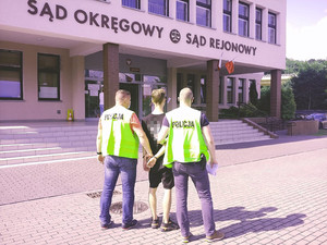 policjanci prowadzą jednego z mężczyzn do budynku sądu rejonowego. W tle budynek sądu.