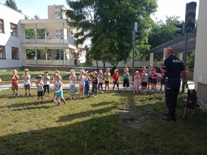 Policjant ćwiczy z grupą dzieci zachowanie podczas ataku psa.