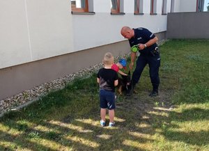 Dzieci głaskają psa policyjnego. w obecności policjanta.