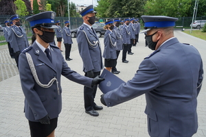 Komendant Miejski wręcza rozkaz w teczce i gratuluje policjantowi