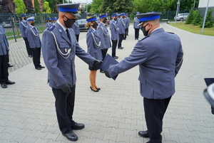 Komendant Miejski wręcza rozkaz w teczce i gratuluje policjantowi