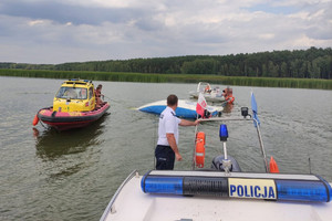 dwie łodzie policyjna i WOPR holują przewrócona na wodzie żaglówkę