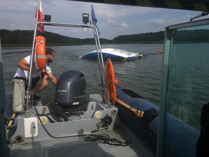 policyjna łódź odholowuje przewróconą żaglówkę