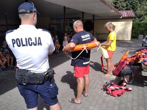 Policjant wraz z instruktorem ratownictwa wodnego prowadzą prelekcję dla młodzieży.