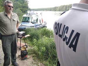 Policjant i leśnik podczas interwencji wobec osób, które rozpaliły grilla w lesie.