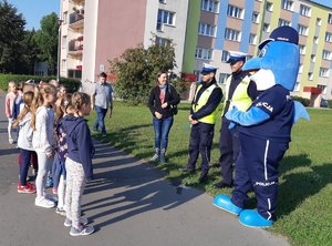 Policjanci wraz z Polfinkiem prowadzą pogadankę z uczniami w rejonie szkoły.