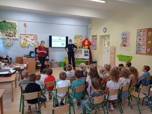 Policjanci prowadzą zajęcia z uczniami siedzącymi w grupie.