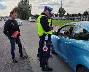 Policjanci oraz Marcin Gagacki podczas akcji stoją przy aucie zatrzymanym do kontroli drogowej.