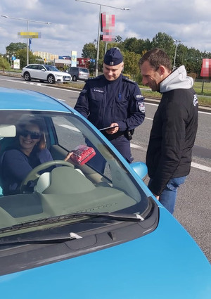Policjant i Marcin Gagacki rozmawiają z kobietą kierującą autem.