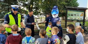 Policjant podaje dzieciom magiczną tubę, przez którą patrzy dziecko.