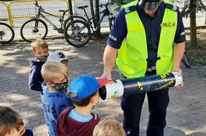 Policjant podaje dzieciom magiczną tubę.