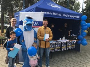 Rodzina pozuje z maskotką bydgoskiej Policji &quot;Polfinkiem&quot;. W tle namiot bydgoskiej policji do spraw doboru.