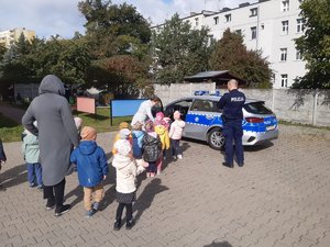 Dzieci oglądają radiowóz zaparkowany na terenie przy przedszkolu.