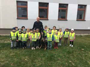 Zdjęcie grupowe dzieci i policjanta z psem służbowym.