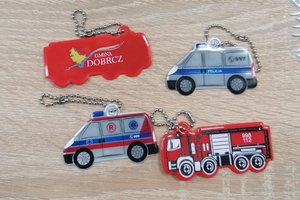 cztery elementy odblaskowe w kształcie radiowozów policji, straży pożarnej, pogotowia ratunkowego oraz pojazdu z napisem Gmina Dobrcz