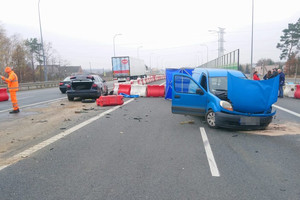 niebieski samochód stoi rozbity na drodze. Obok stoi czarny rozbity pojazd