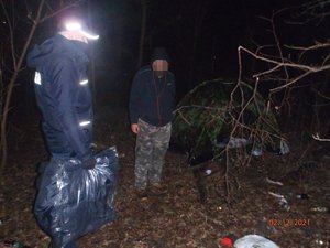 Policjant rozmawia z bezdomnym i trzyma kurtko-śpiwór do przekazania.