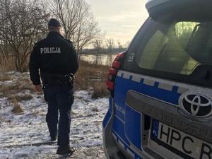 policjant stoi koło oznakowanego radiowozu