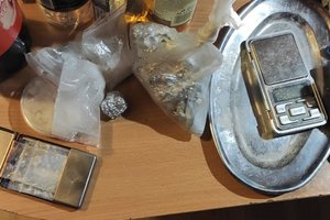 elektroniczna waga, metalowa taca i woreczki z narkotykami leżą na stole